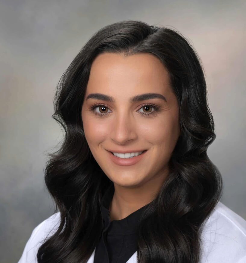 female veterinarian with long brown wavy hair wearing a white lab coat