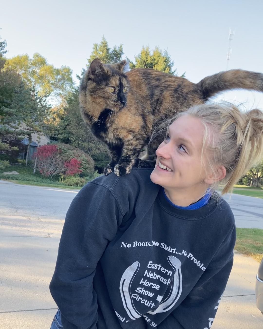 Female with blonde hair in ponytail with a cat standing on her shoulders