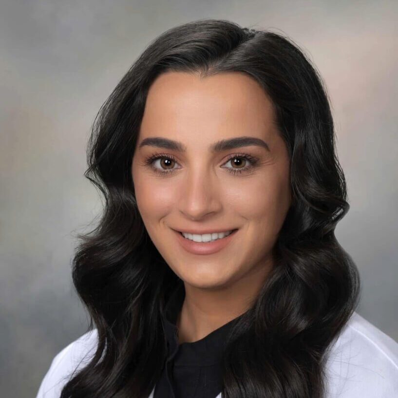 female veterinarian with long brown wavy hair wearing a white lab coat